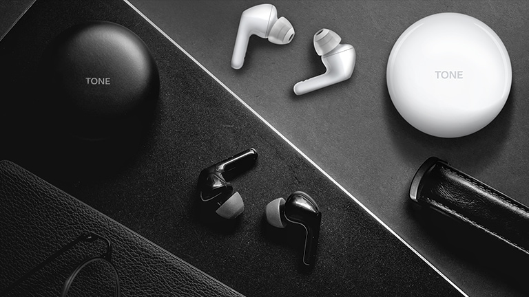 A top view of a desk with black and white earbuds and cradles sitting on top of it