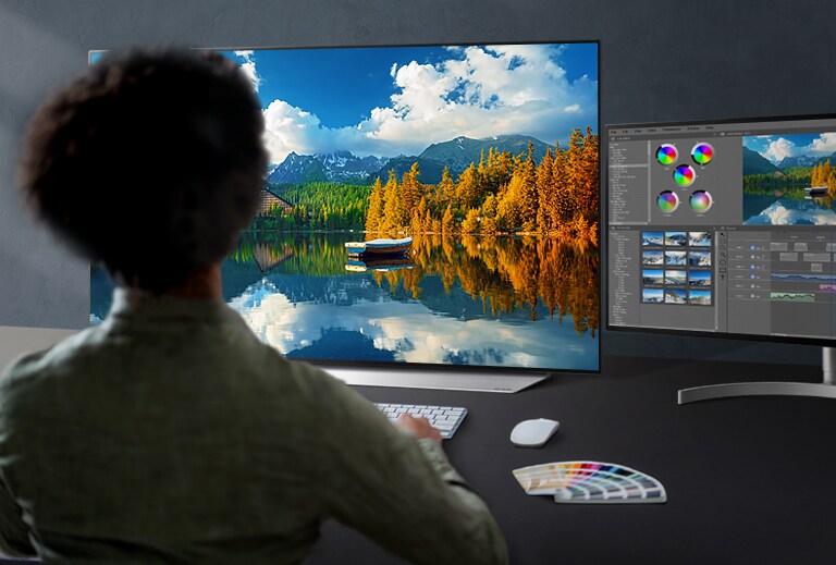 An engineer in a workroom is manipulating the controller to tune an image displayed on a monitor.